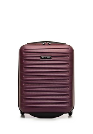 Hard-shell suitcase in deep purple, featuring horizontal ridges, a black zipper, and a logo plate. Four wheels for easy mobility.