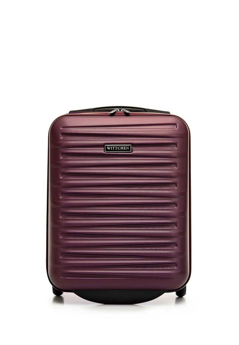 Hard-shell suitcase in deep purple, featuring horizontal ridges, a black zipper, and a logo plate. Four wheels for easy mobility.