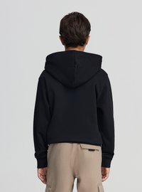 Felpa con cappuccio nera con coulisse, caratterizzata da una texture liscia e una tasca a marsupio, abbinata a pantaloni cargo beige.