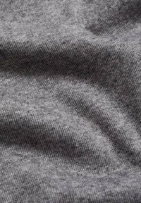 Sivi materijal s mekom, teksturiranom površinom, koji ima dosljedan rebrasti uzorak i suptilne varijacije u nijansama po cijelom materijalu.