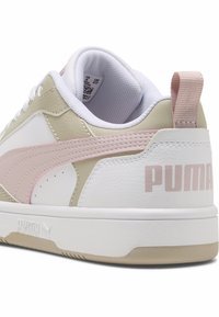 Baskets blanches et beiges avec un accent rose pâle, en matériaux cuir et textile, bout rond, col rembourré et logo bien en vue sur le talon.