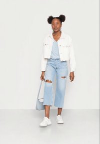 Vitcroppad denimjacka, ljusblå henley-tröja, slitna ljusblå jeans, vita sneakers och en ljusblå axelväska.