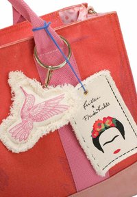 Sac fourre-tout en toile corail et rose, orné d'un écusson cousu représentant un colibri et d'une étiquette avec le visage de Frida Kahlo et une couronne de fleurs.