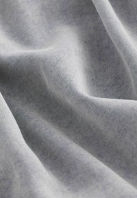 Denim stof in lichtgrijs, met een gladde textuur en subtiele diagonale ribbels, evenals lichte variaties in kleurverzadiging.