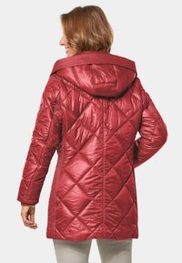 Rode gewatteerde jas met een capuchon, een ruitpatroon en textuurlijsten. Het materiaal lijkt glanzend en soepel, met een middellange snit.