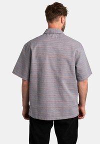Camisetta a maniche corte in azzurro chiaro con righe orizzontali in diverse tonalità. Presenta un colletto e una vestibilità rilassata.
