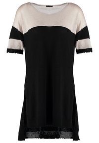 T-shirt à manches courtes en noir et beige métallisé, avec un col rond, des fentes sur les côtés et un ourlet noir texturé, avec des sections de couleurs alternées.