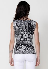 Top fără mâneci cu un model alb și negru, înfățișând o combinație de desene florale și abstracte, având o croială ajustată și o textură netedă.