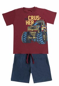 Rode T-shirt met een monstertruckgrafiek in blauw en geel, gecombineerd met marineblauwe shorts met een trekkoord in de taille.