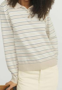 Polo beige à manches longues avec des rayures horizontales noires et marron clair, doté d'une patte de boutonnage à trois boutons et d'un tissu tricoté texturé.