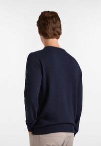 Jersey azul marino con manga larga, cuello redondo y puños acanalados. Textura suave, diseño ajustado, adecuado para el uso casual.