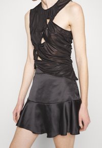 Svart klänning med lagerdesign i genomskinliga och satin texturer, utan ärmar, med en tight överdel och utsvängd kjol.