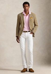 Beige herringbone blazer, pink polo, white slim-fit jeans, brown belt, brown loafers. Pocket square adds detail. Smooth textures throughout.