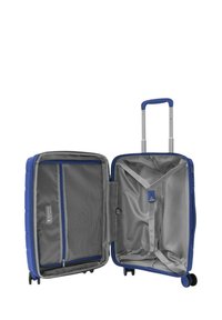 Valigia rigida blu con manico telescopico, quattro ruote e interno grigio dotato di tasche in rete e una cinghia incrociata per fissare il contenuto.