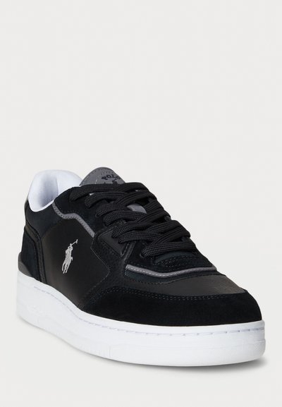 Chaussure de sport noire avec une tige en suede et synthétique, dotée d'une semelle blanche, de panneaux texturés et d'un logo de marque sur le côté.