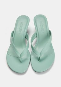 Infradito verde menta con finitura liscia e opaca, design minimalista e fasce sottili con un puntale a forma di Y.