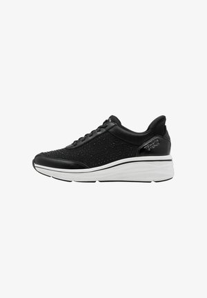 Black sneaker with perforated fabric upper, smooth leather accents, white cushioned sole, and textured detailing along the sole’s edge.