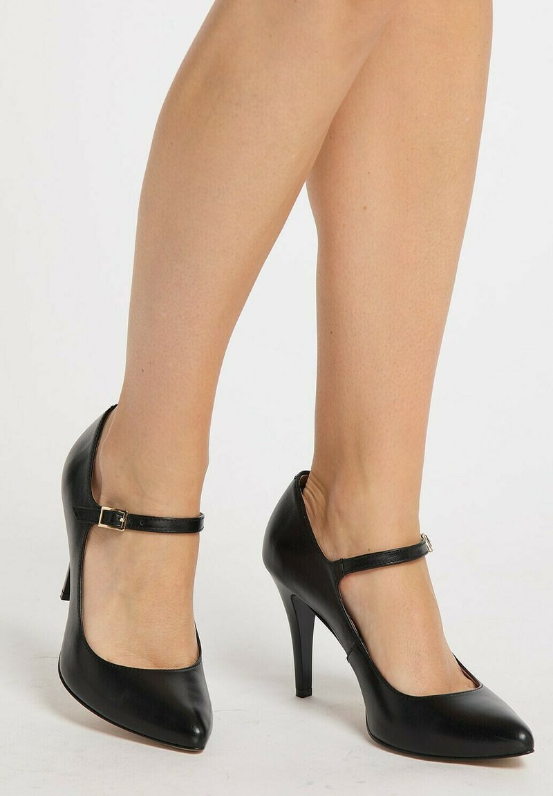 Sorte læder højhælede sko med spidse tæer, ankelstrop med en gylden spænde og en slank stiletto hæl, glat tekstur, elegant design.