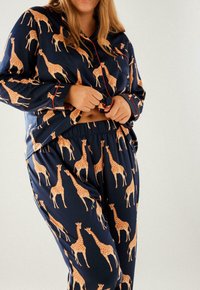 Navy pajama set made of soft fabric, featuring orange giraffe patterns, with a button-up top and elastic waistband pants.