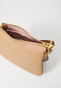 Borsa in pelle marrone chiaro con superficie texturizzata, hardware dorato e chiusura con zip. L'interno è foderato in tessuto rosa chiaro.
