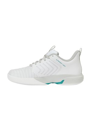 Witte lage sportschoen met grijze accenten, getextureerde neus, chevron-patronen aan de zijkant en turquoise details op de zool.