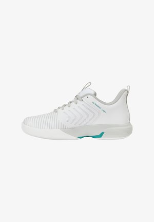Chaussure de sport basse blanche avec des accents gris, un bout texturé, des motifs en chevrons sur le côté et des détails turquoise sur la semelle.