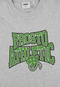 Szara bawełniana koszulka z wyraźnym zielonym nadrukiem tekstowym "PROSTO ATHLETIC" z zielonym wzorem koniczyny splecionym z literami.