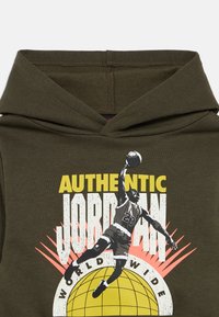 Ελαιόλαδο πράσινη κουκούλα φούτερ με γραφικό ενός παίκτη μπάσκετ, κείμενο "AUTHENTIC JORDAN WORLD WIDE" και σχέδιο σφαίρας.