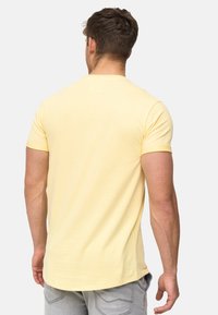 Short-sleeve, light yellow T-shirt made of soft fabric. Features a classic crew neckline and a relaxed fit. Simple, solid color design.