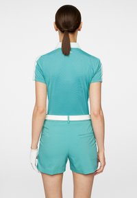 Ljusblå golfutrustning med en pikétröja med kort ärm och vit krage samt matchande shorts. Materialet verkar mjukt med en slät struktur.