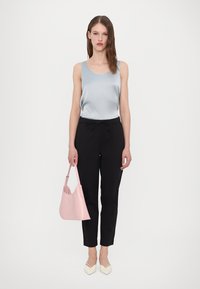 Light blue satin top, black tailored pants, and a light pink handbag. Person wears cream-colored heels. Simple, modern design throughout.