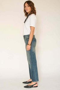 T-shirt blanc, jean en denim bleu taille haute et chaussures slingback noires avec découpes circulaires. Le jean présente une silhouette à jambes droites.
