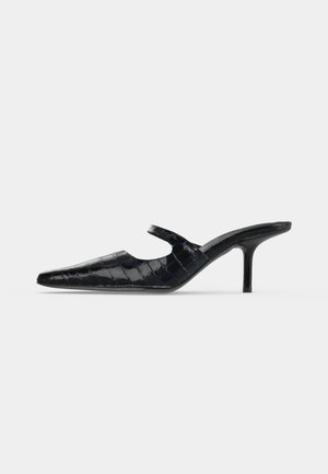Mule en cuir verni noir avec texture crocodile, bout pointu et talon fin de hauteur moyenne, vue de côté sur fond clair.