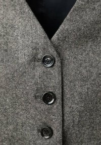 Grau strukturiertes Stoffwesten-Design mit tiefem V-Ausschnitt und drei schwarzen Knöpfen vorne, mit einem eleganten inneren Futter in Schwarz.