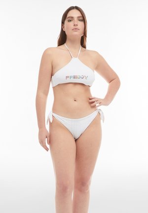 Valkoinen bikinit, joissa on naruolkaimet ja 'FREDDY'-logo värikkäillä kirjaimilla. Alaosassa on pieniä pallokuvioita ja solmimisdetailleja sivuilla.