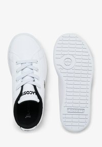 White Lacoste sneaker shown from top and bottom, featuring laces, black interior lining, and textured sole with brand name.
