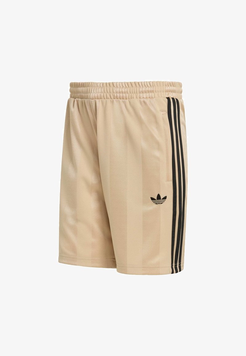 Pantalones cortos deportivos beige con rayas verticales negras, cintura elástica y un pequeño logo negro en la pierna izquierda. Textura suave y diseño ajustado.