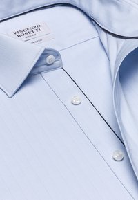 Lichtblauwe, getailleerde button-up shirt met een herringbone patroon, kraag en zwarte accentpiping langs de voorplacket.