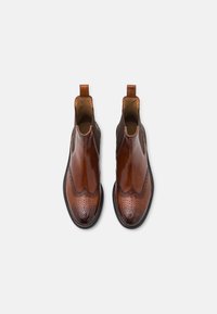 Bottes chevilles en cuir marron avec une finition brillante, présentant un design festonné et un motif perforé, des panneaux latéraux élastiques et des languettes de tirage.