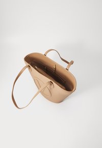 Μπεζ δερμάτινη τσάντα ώμου με υφή και αποσπώμενη τσάντα με φερμουάρ, διαθέτοντας δύο λουριά ώμου και κυκλικό λογότυπο στο μπροστινό μέρος.