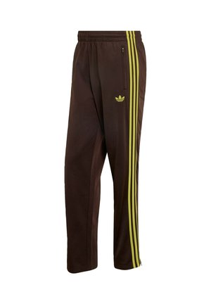 Pantaloni da allenamento marrone scuro con tre strisce verticali verde lime sul lato, tasca con zip, vita elastica e logo Adidas sulla coscia.