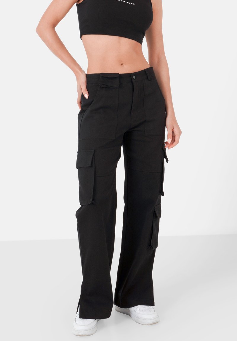 Zwarte katoenen cargobroek, met zijzakken, een recht gesneden pijp en een hoge taille. De textuur is glad met minimale stikseldetails.
