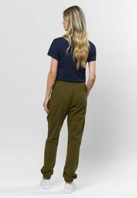 Marineblauwe crewneck t-shirt gecombineerd met olijfgroene joggers met een taps toelopend been, elastische boorden en witte sportschoenen.