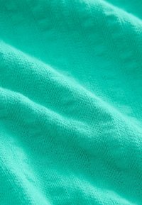 Teksturoidu, turkoosi kangas, jossa on sileä pinta; siinä on hienovarainen, toistuva kuvio ja pehmeä roikkuminen, mikä tekee siitä ihanteellisen vaatteisiin tai verhoiluun.