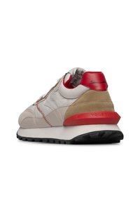 Sneaker beige con accenti rossi, materiali in suede e pelle, forma arrotondata, superficie texturizzata, intersuola bianca, suola in gomma nera.
