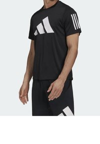 Camiseta deportiva negra con logo geométrico blanco. Las mangas cortas tienen tres rayas blancas. Fabricada con un tejido suave y transpirable.