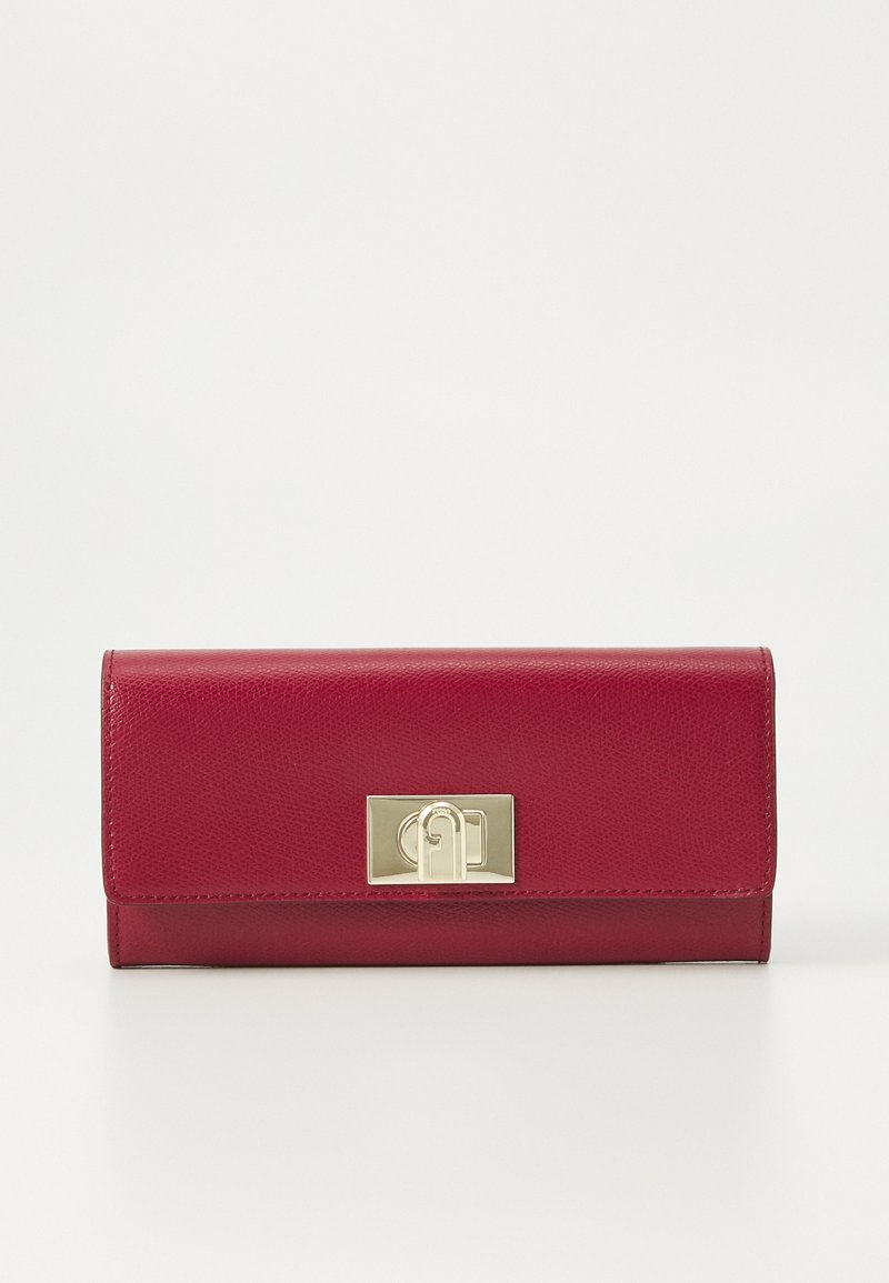 Portofel roșu din piele cu o textură distinctă, având un clemă din metal auriu și o formă rectangulară. Design minimalist, fără modele vizibile.