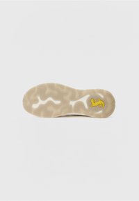 Sneaker-Außensohle in hellem Beige mit welligem Profilmuster. Verfügt über eine strukturierte Oberfläche und ein gelbes Logo-Detail.