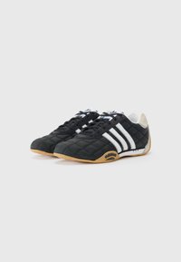 Black synthetic shoes with a quilted texture, white three-stripe design, rubber sole, and cushioned heel. Features a rounded toe.