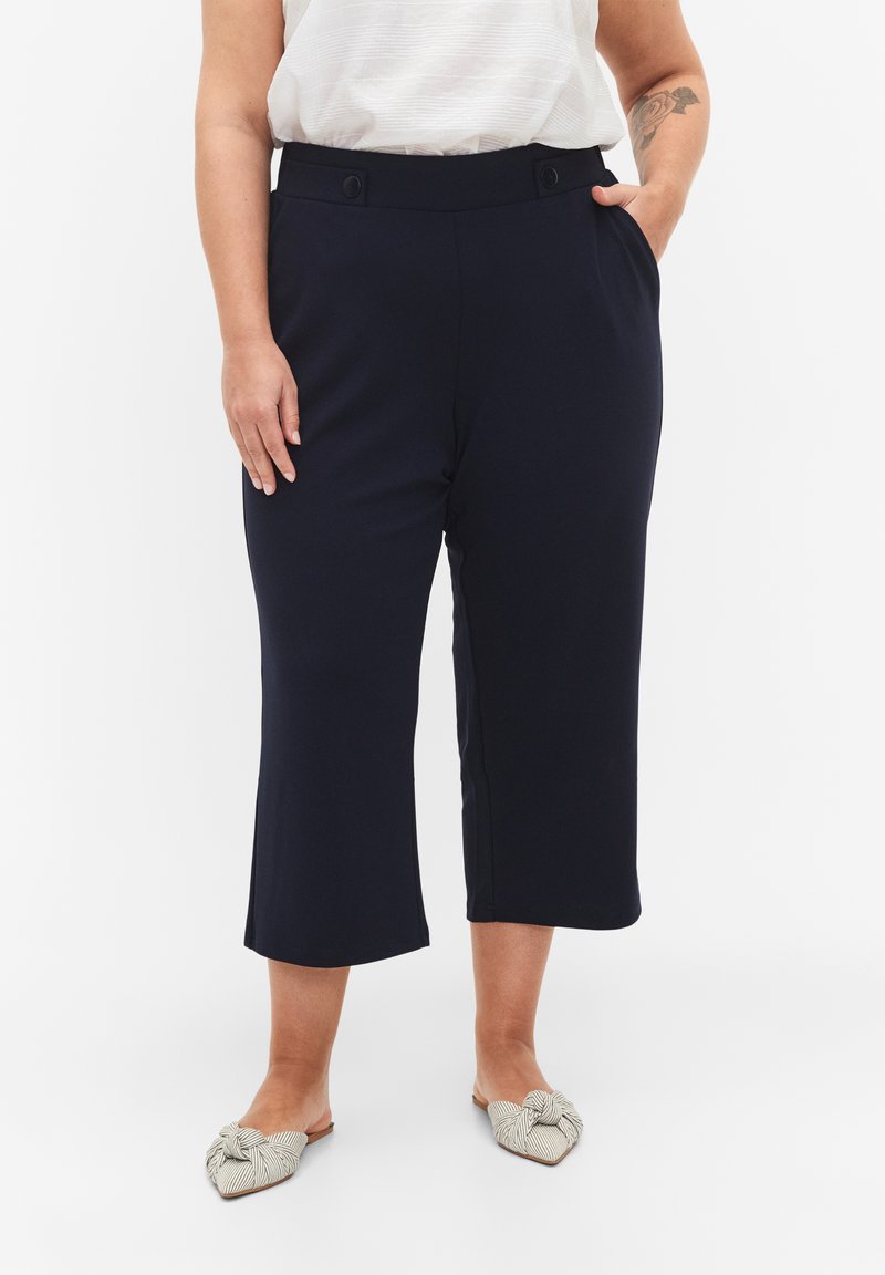Marineblauwe cropped broek van rekbare stof met een gladde textuur, voorzien van zijzakken, twee knopen op de taille en een relaxte pasvorm.